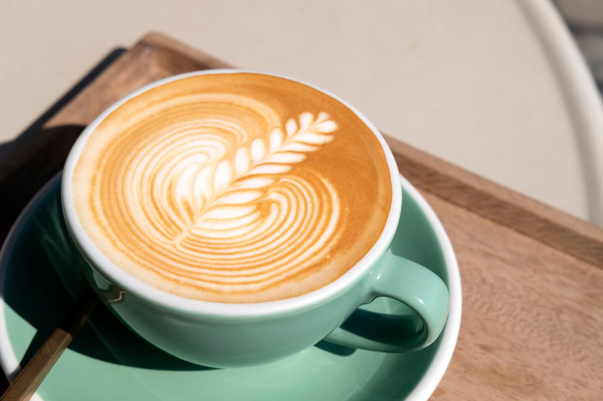 Hot latte with beautiful latte art in a green cup